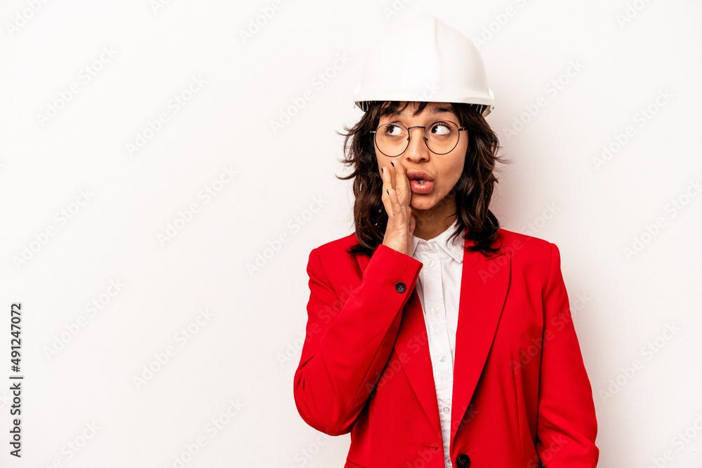 Young architect hispanic woman with helmet isolated on white background is saying a secret hot braking news and looking aside Young architect hispanic woman with helmet isolated on white background is saying a secret hot braking news and looking aside