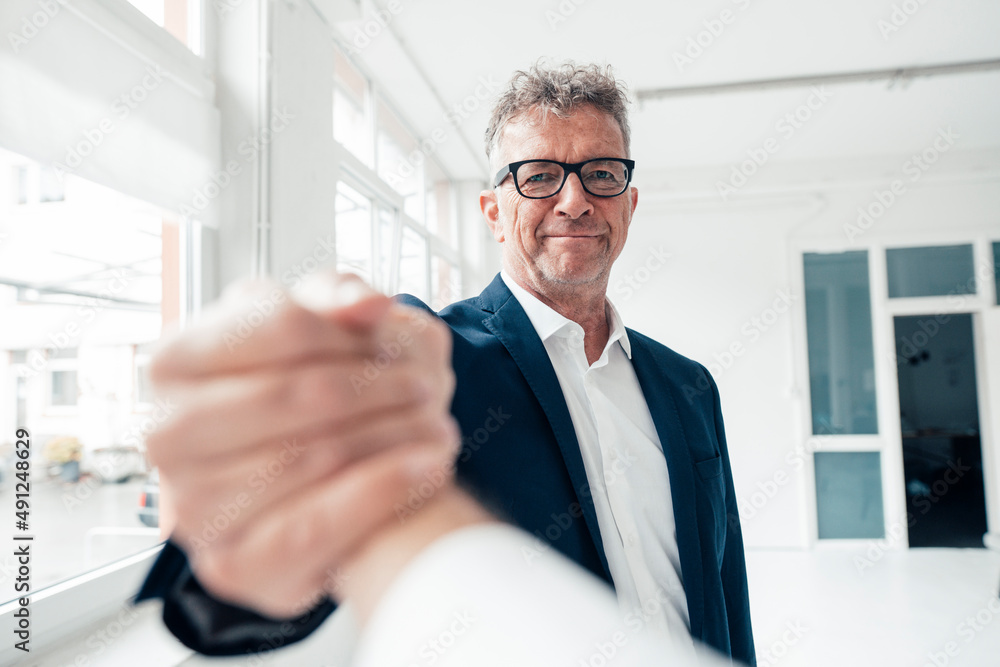 Smiling businessman holding hand of colleague at work place Smiling businessman holding hand of colleague at work place