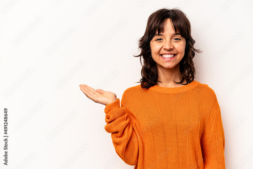 Young hispanic woman isolated on white background showing a copy space on a palm and holding another hand on waist. Young hispanic woman isolated on white background showing a copy space on a palm and holding another hand on waist.
