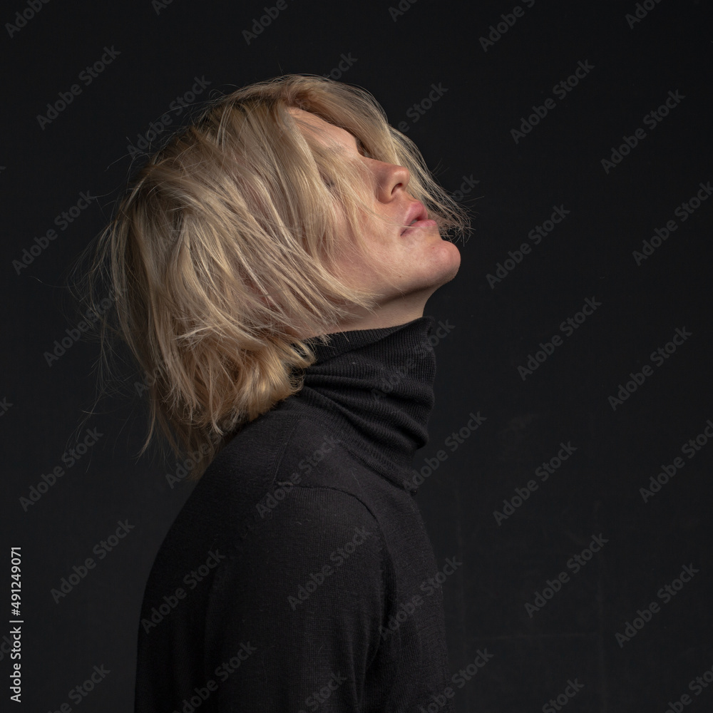 Obraz premium portrait of a young attractive man with blond hair in dark clothes on a dark background