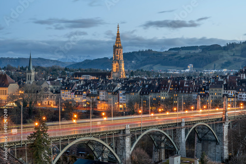 Switzerland, Canton of Bern, Bern, Kornhausbrucke bridge at dusk with bell tower of Cathedral of Bern in background photo