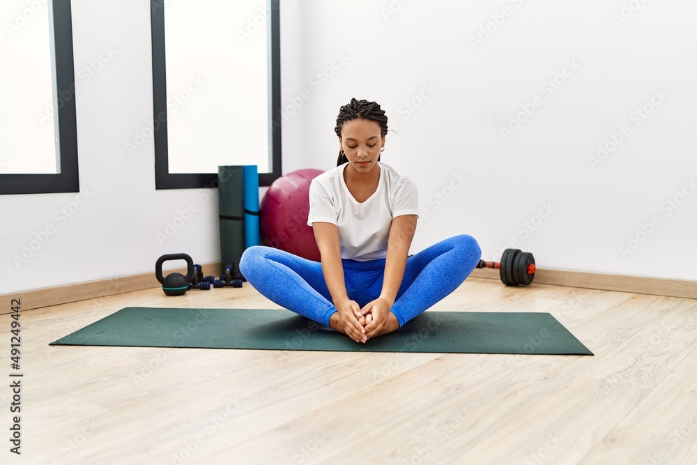 Young african american woman stretching at sport center