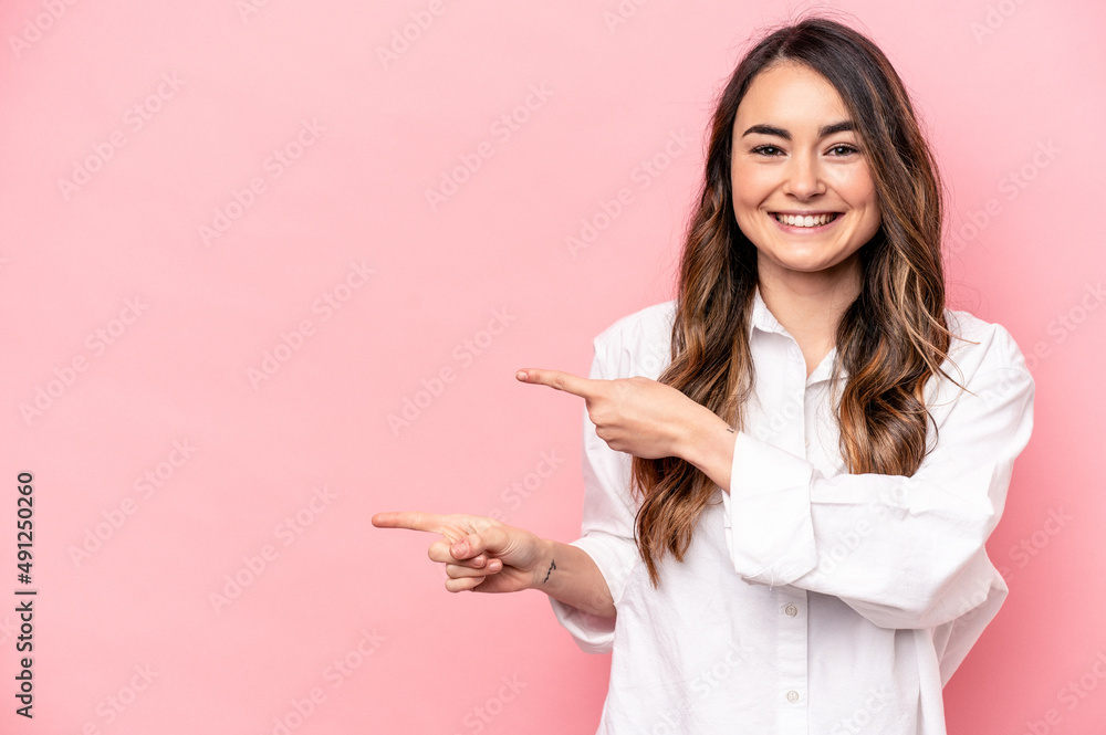 Young caucasian woman isolated on pink background excited pointing with forefingers away.