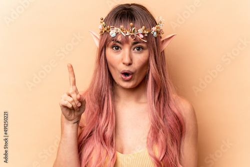 Young elf woman with pink hair isolated on beige background having some great idea, concept of creativity.