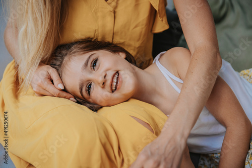 Smiling daughter lying on mother's lap at patio photo