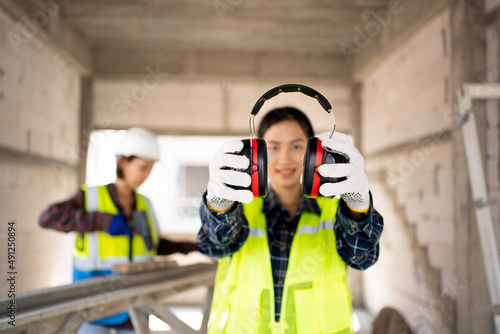 Pretty Asian Engineer,foreman Campaign to wear soundproofing equipment.Recommendations for wearing ear muffs.
Work safely with noise reduction.
a young woman using an electric screwdriver safely.