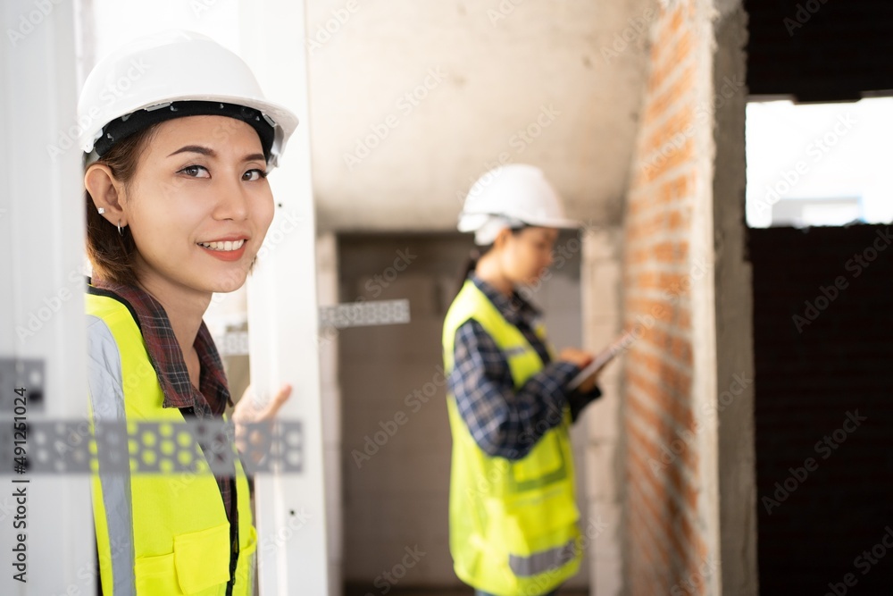 © Chalermphon - worker woman wears a white hard hat look up.female construction inspector reviews a masonry during home inspection as she holding clipboard.team civil engineerใTwo women work together to inspect.