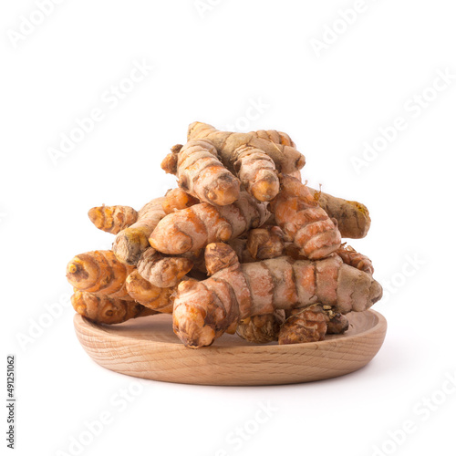 turmeric roots, traditional southeast asian spice on a wooden plate, also known for medicinal purposes, isolated on white background