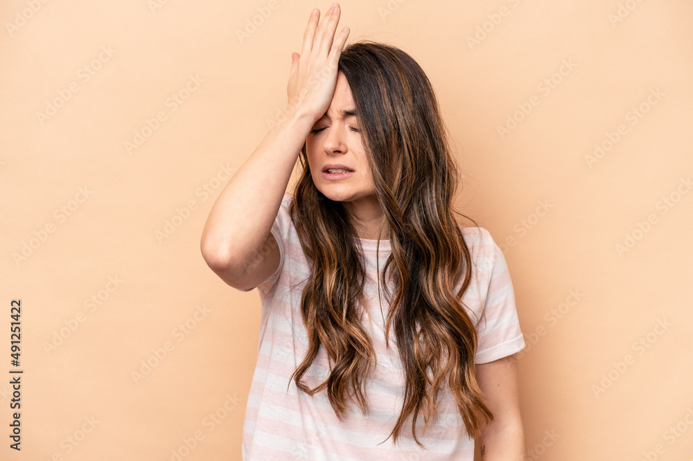 Young caucasian woman isolated on beige background forgetting something, slapping forehead with palm and closing eyes.