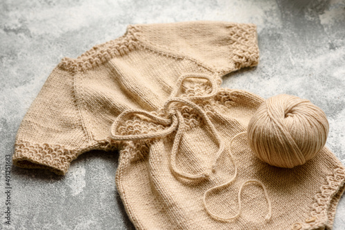 Baby knitted beige clothes on a white concrete background