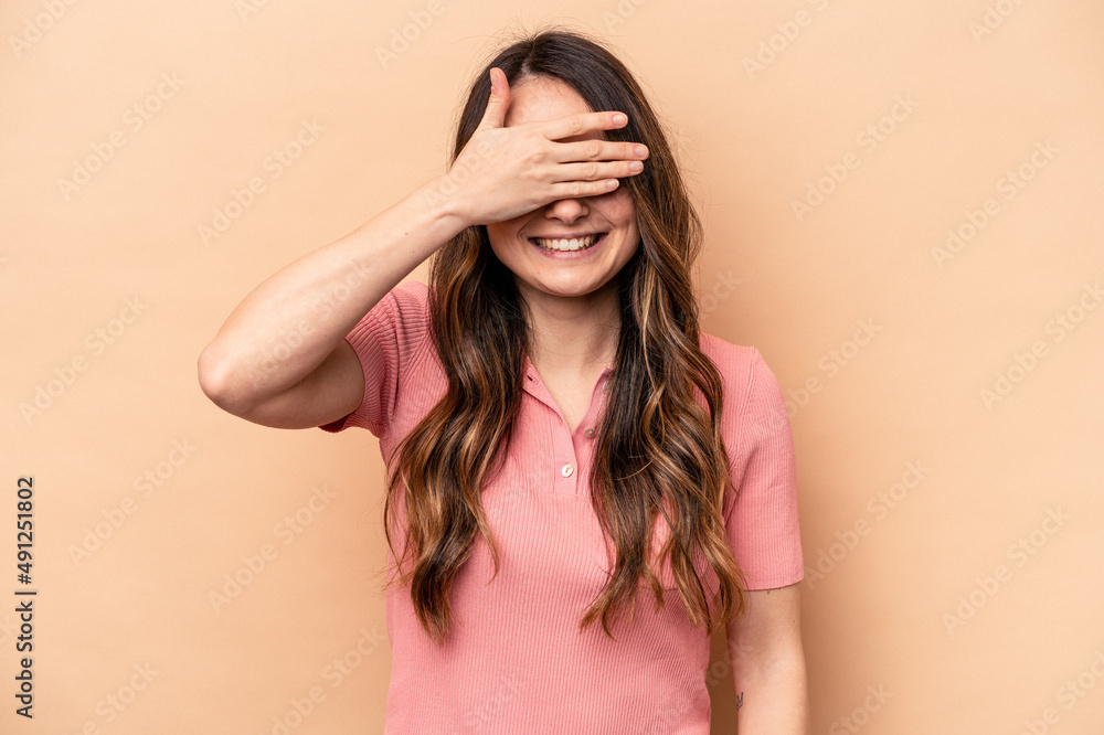 Young caucasian woman isolated on beige background covers eyes with hands, smiles broadly waiting for a surprise. Young caucasian woman isolated on beige background covers eyes with hands, smiles broadly waiting for a surprise.
