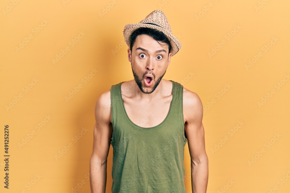 Young hispanic man wearing summer hat afraid and shocked with surprise expression, fear and excited face. Young hispanic man wearing summer hat afraid and shocked with surprise expression, fear and excited face.