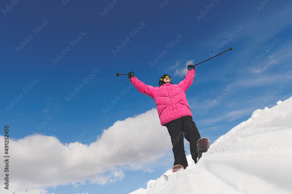 Man with arms raised holding ski poles standing on snow