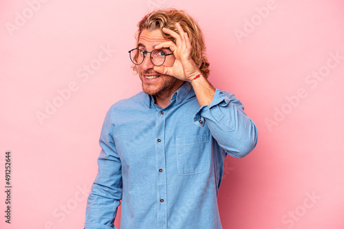 Young caucasian man isolated on pink background excited keeping ok gesture on eye.