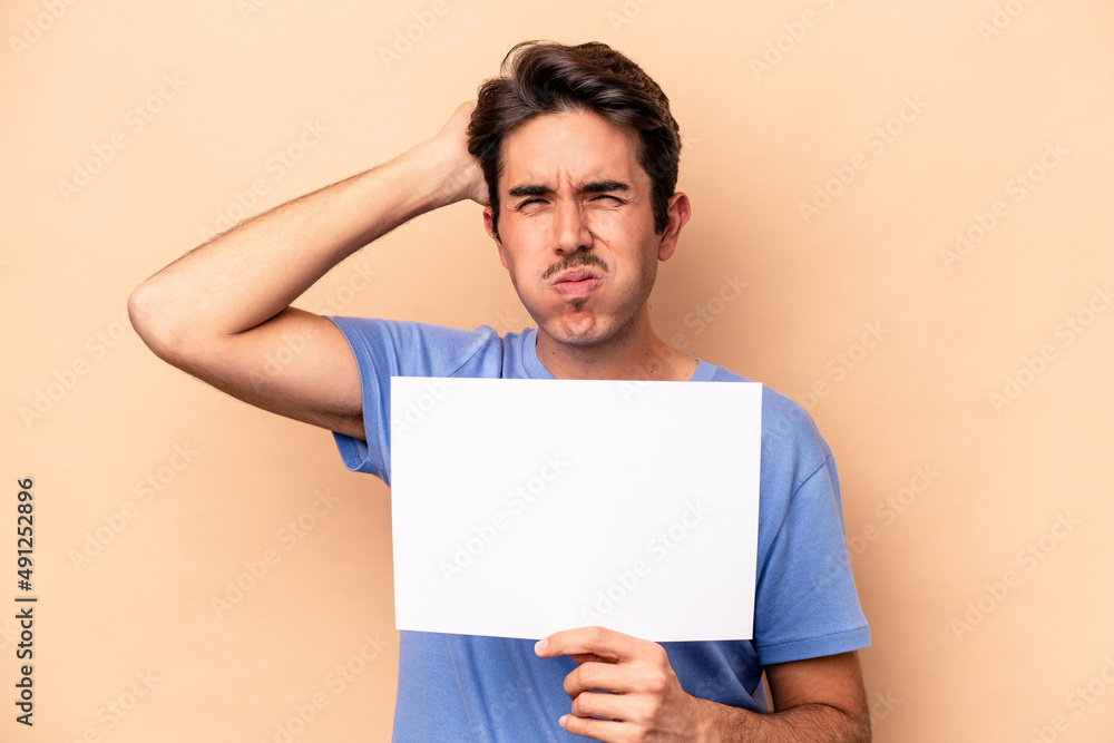 Young caucasian man holding a placard isolated on beige background being shocked, she has remembered important meeting. Young caucasian man holding a placard isolated on beige background being shocked, she has remembered important meeting.