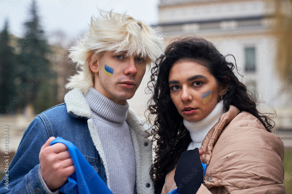 Obraz premium Portrait of caucasian couple with Ukrainian flags on cheeks
