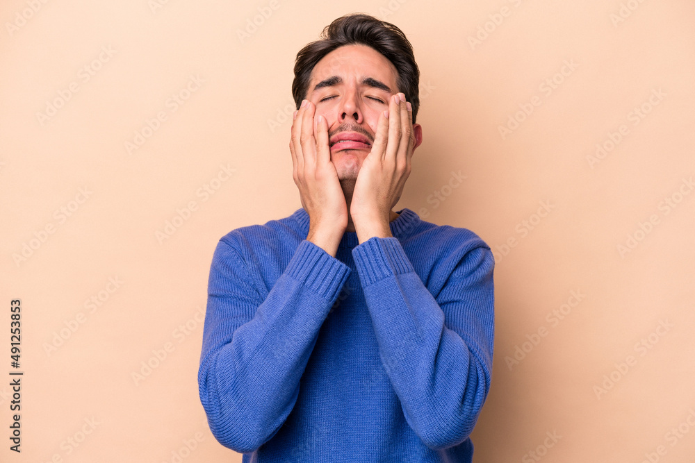Young caucasian man isolated on beige background crying, unhappy with something, agony and confusion concept. Young caucasian man isolated on beige background crying, unhappy with something, agony and confusion concept.