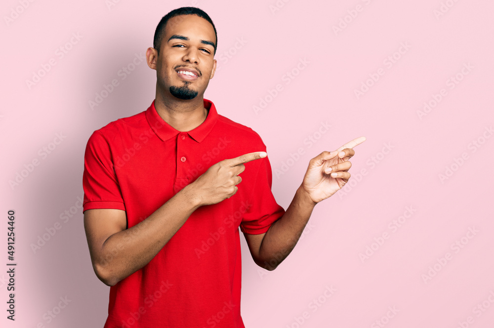 Young african american man wearing casual polo smiling and looking at the camera pointing with two hands and fingers to the side. Young african american man wearing casual polo smiling and looking at the camera pointing with two hands and fingers to the side.
