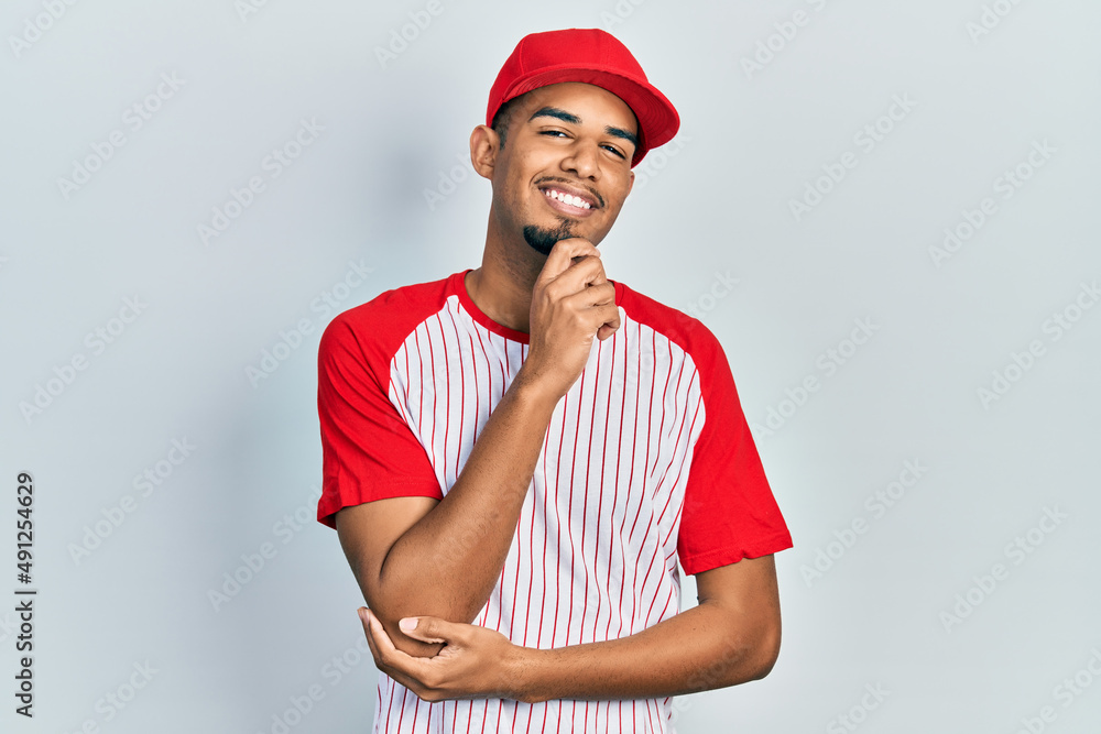 Young african american man wearing baseball uniform screaming proud, celebrating victory and success very excited with raised arms Young african american man wearing baseball uniform screaming proud, celebrating victory and success very excited with raised arms