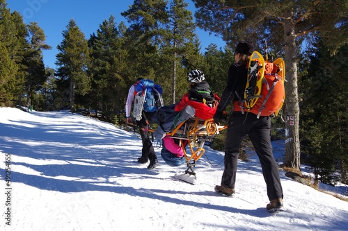 Randonnée solidaire avec handicapés en fauteuil roulant et aveugles sur la neige avec des raquettes et des patins en montagne en hiver photo