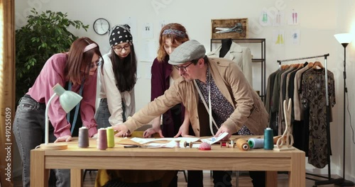 The work of fashion designer and tailors in the shop. Fashion designers working in their studio. Colorful Fabrics, Clothes Hanging and Sewing Items are Visible. photo