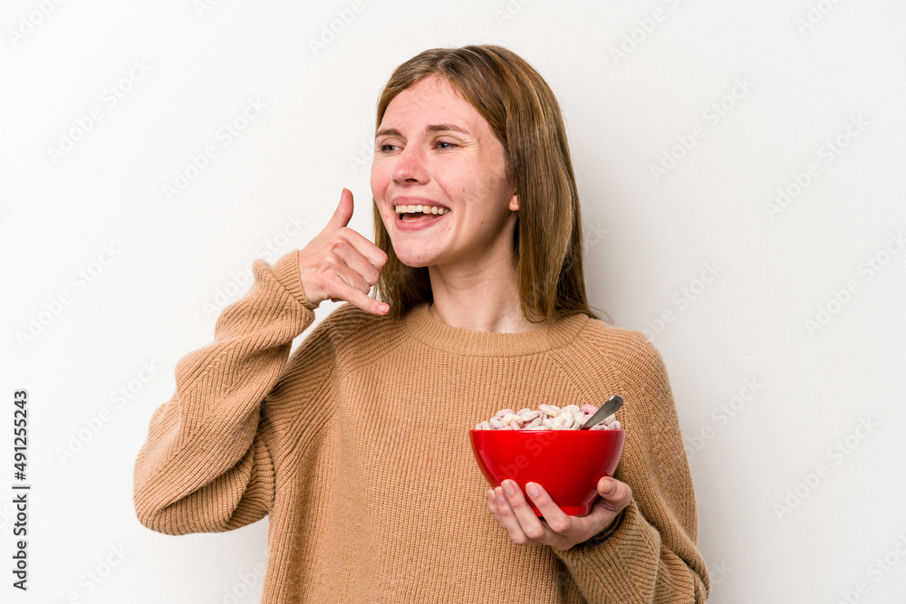 Young English woman eating cereals isolated on white background showing a mobile phone call gesture with fingers. Young English woman eating cereals isolated on white background showing a mobile phone call gesture with fingers.