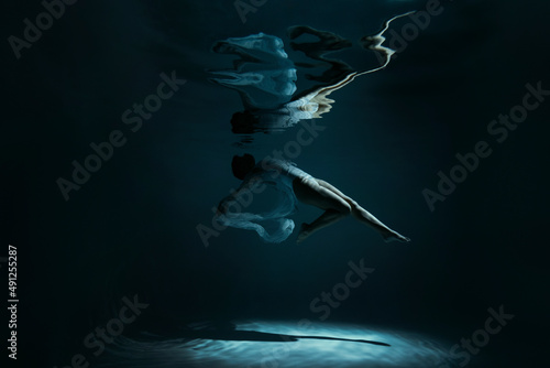 Young woman with reflection swimming undersea
