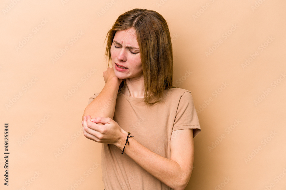 Obraz premium Young English woman isolated on beige background massaging elbow, suffering after a bad movement.