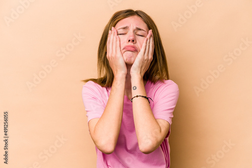 Young English woman isolated on beige background whining and crying disconsolately.
