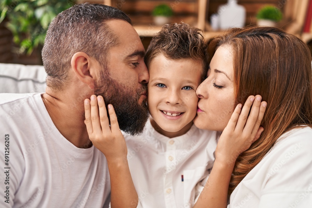 Fototapeta premium Family kissing and hugging each other sitting on sofa at home