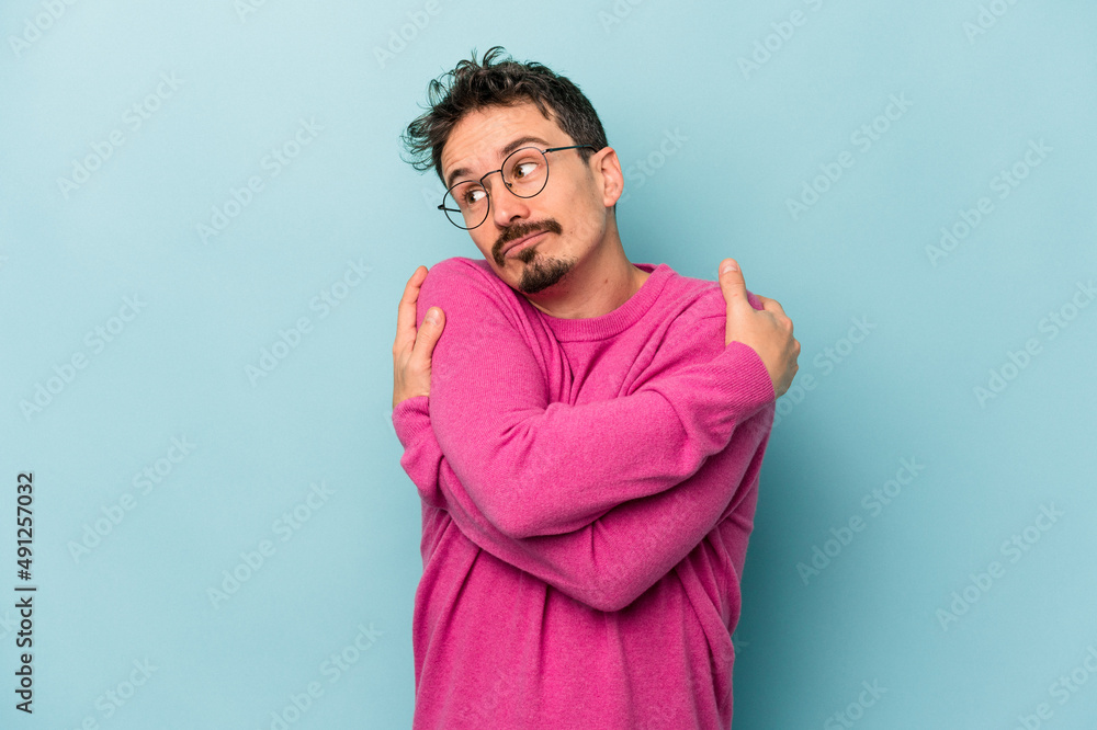 Young caucasian man isolated on blue background hugs, smiling carefree and happy. Young caucasian man isolated on blue background hugs, smiling carefree and happy.
