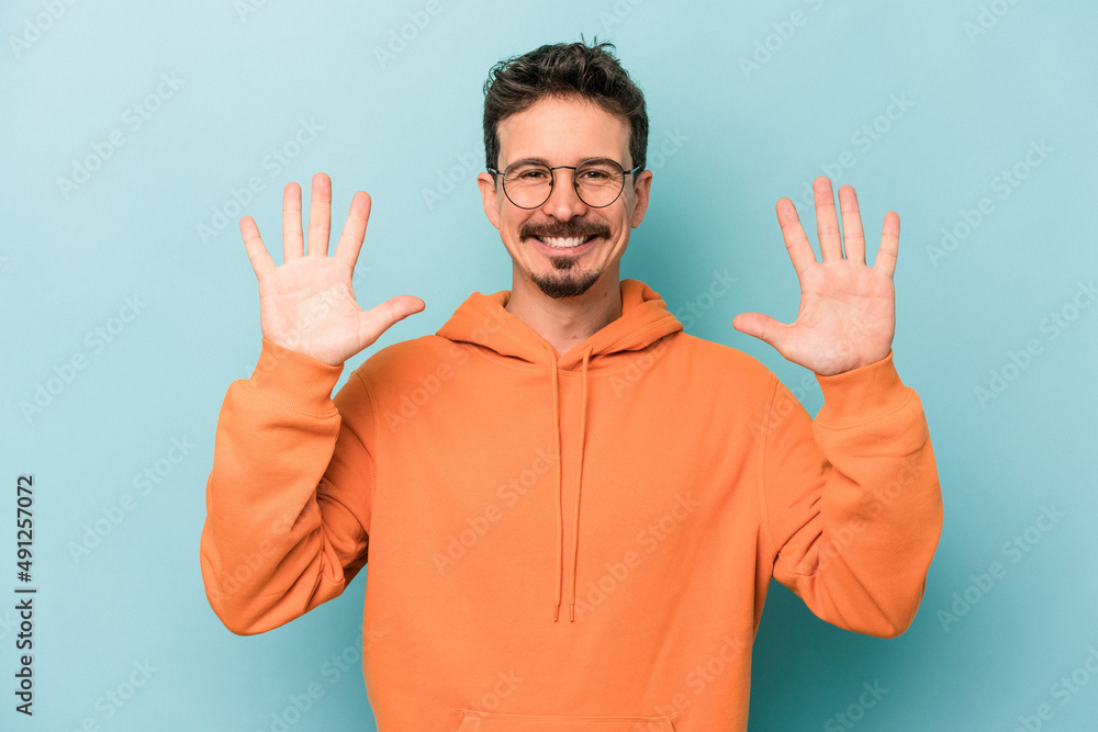 Young caucasian man isolated on blue background showing number ten with hands. Young caucasian man isolated on blue background showing number ten with hands.