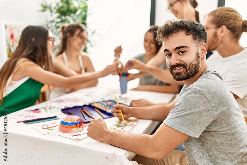 Group of young paint students smiling happy and drawing sitting on the table at art studio. Group of young paint students smiling happy and drawing sitting on the table at art studio.