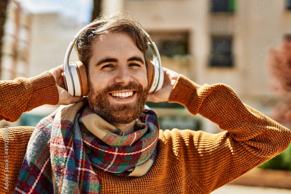 Young caucasian man with beard listening to music wearing headphones  outdoors on a sunny day Stock Photo | Adobe Stock