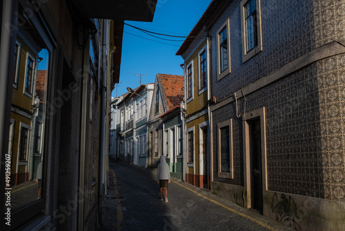 A boy on a narrow street residential house with tiles on the facade