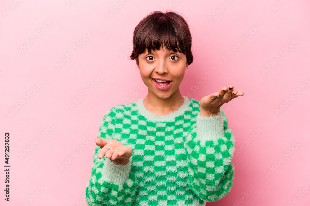 Young hispanic woman isolated on pink background makes scale with arms, feels happy and confident. Young hispanic woman isolated on pink background makes scale with arms, feels happy and confident.