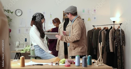 The work of fashion designer and tailors in the shop. Fashion designers working in their studio. Colorful Fabrics, Clothes Hanging and Sewing Items are Visible. photo