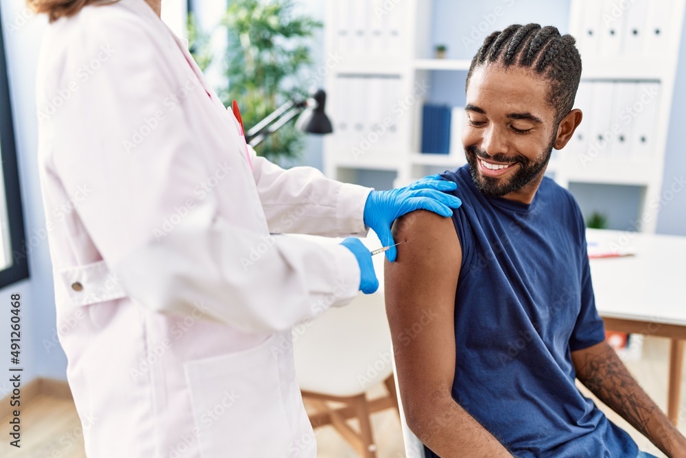Fototapeta premium Man and woman wearing doctor uniform vaccinating at clinic