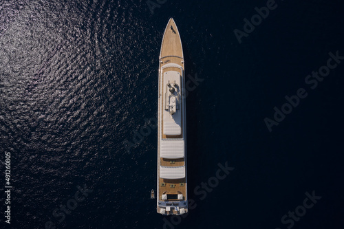 Big yacht for millionaires in the sea drone view. Luxurious white mega yacht on dark water in the reflection of the sun top view. Big white super ship in the dark ocean aerial view. © Berg