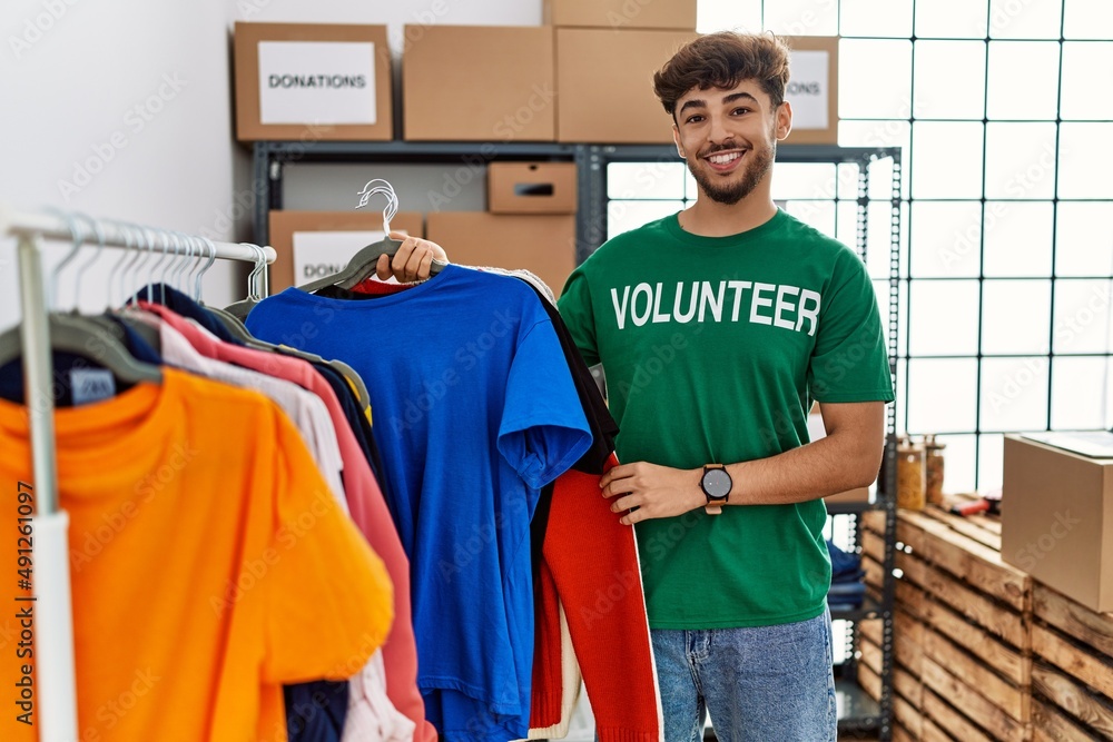 Young arab man wearing volunteer uniform working at charity center Young arab man wearing volunteer uniform working at charity center