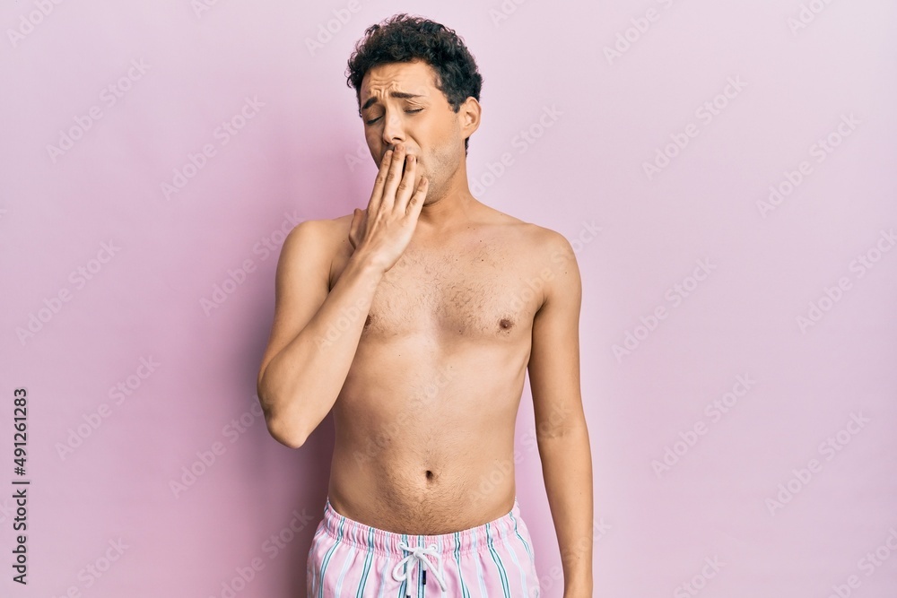 Fototapeta premium Young handsome man wearing swimwear shirtless bored yawning tired covering mouth with hand. restless and sleepiness.