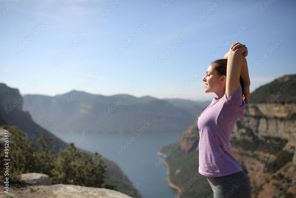 Sportswoman stretching arms in a beautiful landscape Sportswoman stretching arms in a beautiful landscape