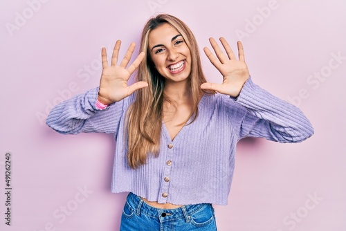 Beautiful hispanic woman wearing casual shirt showing and pointing up with fingers number ten while smiling confident and happy.