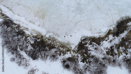 Aerial view of the beginning of the outflow of water from the banks of the river as a result of melting ice and snow in early March