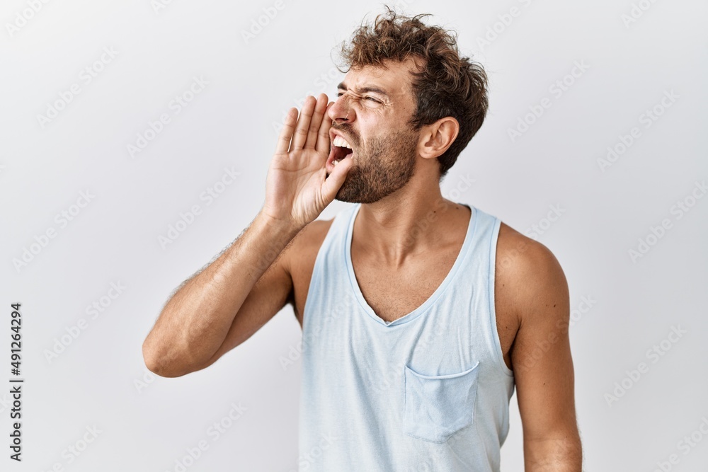 Naklejka premium Young handsome man standing over isolated background shouting and screaming loud to side with hand on mouth. communication concept.