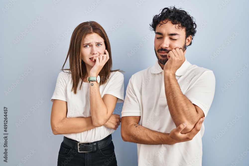 Young couple wearing casual clothes standing together looking stressed and nervous with hands on mouth biting nails. anxiety problem. Young couple wearing casual clothes standing together looking stressed and nervous with hands on mouth biting nails. anxiety problem.