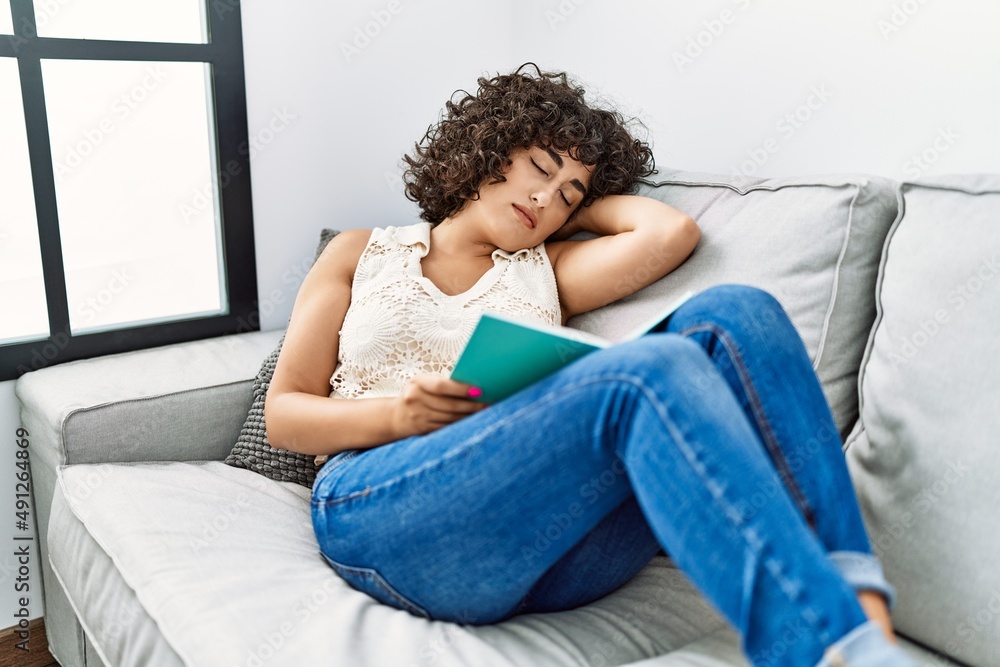 Young middle east woman sleeping with book on hands at home