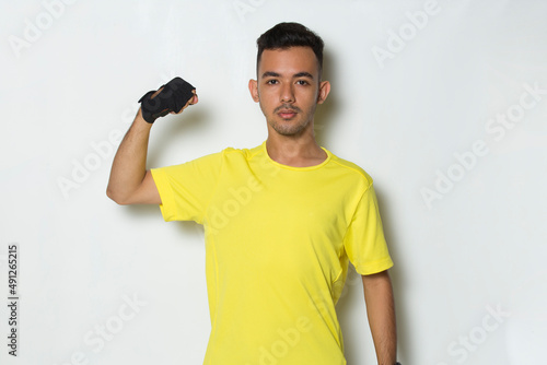 young sporty man dressed in yellow tshirt showing strong gesture on white background 