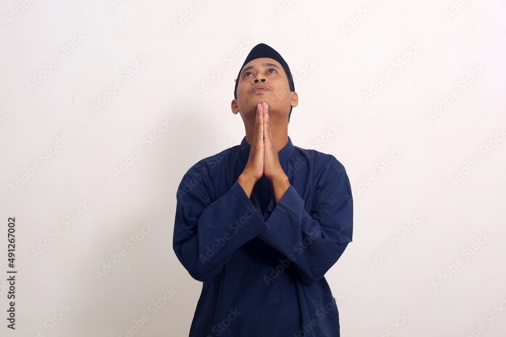 Young asian man of muslim religion praying isolated on white background Young asian man of muslim religion praying isolated on white background