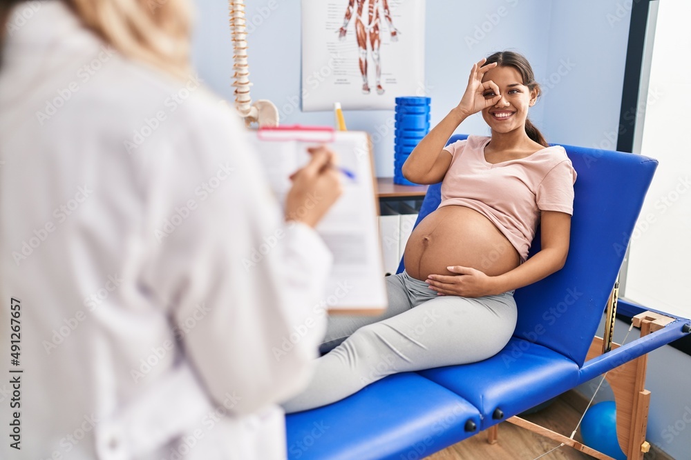 Obraz premium Young pregnant woman at physiotherapist clinic celebrating crazy and amazed for success with open eyes screaming excited.